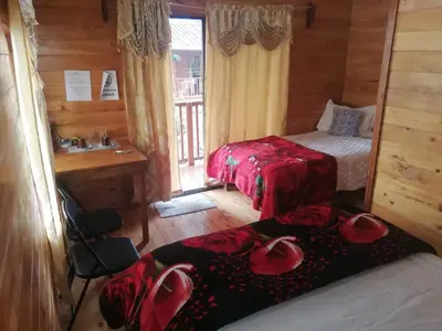 a bedroom with two beds and a bathroom with a window at Cabañas San Gerardo in San Gerardo de Dota