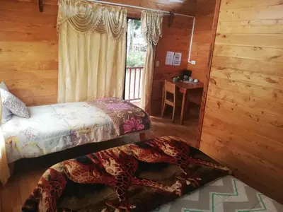 a bedroom with two beds and a window with a desk at Cabañas San Gerardo in San Gerardo de Dota