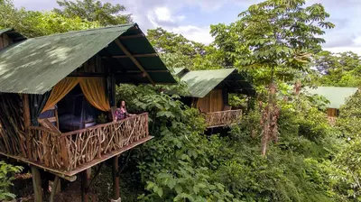 a woman standing on the balcony of a tree house at La Tigra Rainforest Lodge in Fortuna
