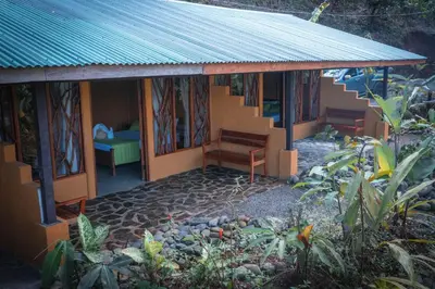 a small house with a bench and a bed at La Tigra Rainforest Lodge in Fortuna