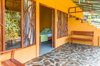 a porch of a house with a bed and a bench at La Tigra Rainforest Lodge in Fortuna
