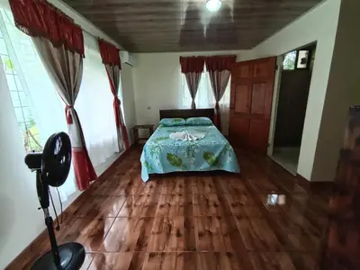 a bedroom with a bed and wooden floors and windows at Posada Rural Río Celeste in Rio Celeste