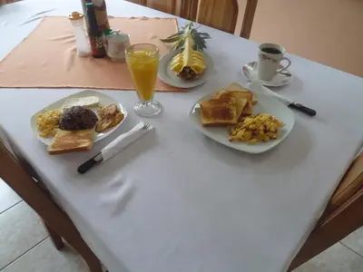 a table with two plates of breakfast foods and a glass of orange juice at Posada Rural Río Celeste in Rio Celeste