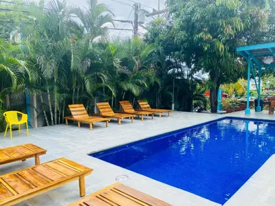 a pool with wooden chairs and a bunch of trees at Hotel Diversion Tropical in Brasilito