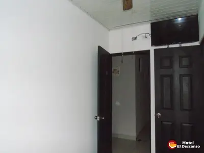 a room with a tv on the wall and a door at Hotel El Descanso in San José