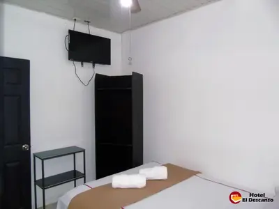 a bedroom with a bed and a flat screen tv at Hotel El Descanso in San José