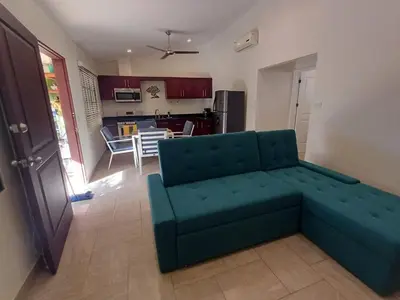 a living room with a green couch and a kitchen at Guest House in Playa Flamingo