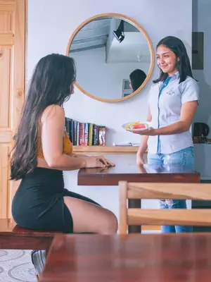 a woman is handing a plate of food to a waitress at Hotel Alicia in Fortuna