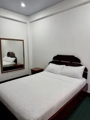 a bedroom with a white bed and a mirror at Hotel Malinche in Quepos