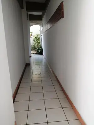 a corridor of a room with white walls and white tile floors at Hotel Malinche in Quepos