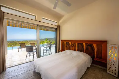 a bedroom with a bed and a balcony with a table and chairs at Casa Laureles in Bejuco