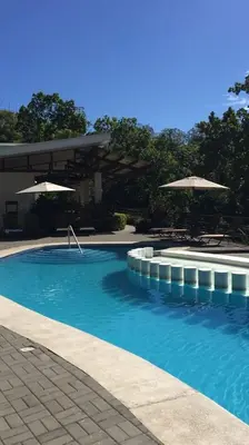 a swimming pool with blue water and umbrellas at Villa privada con hidromasaje Herradura Jaco in Herradura