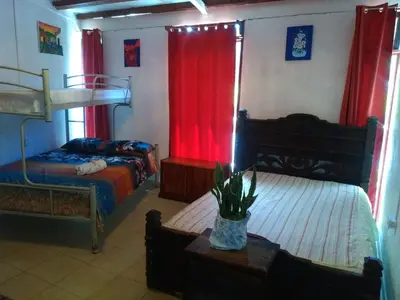 a bedroom with two beds and red curtains at Hostel Paco House in Monteverde Costa Rica
