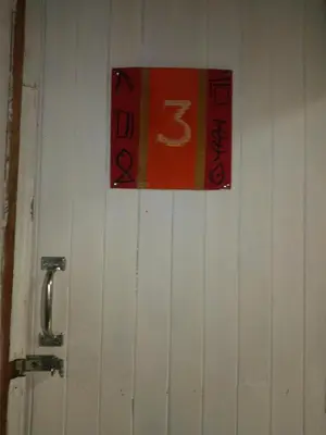 a sign on a white wall with a number on it at Hostel Paco House in Monteverde Costa Rica