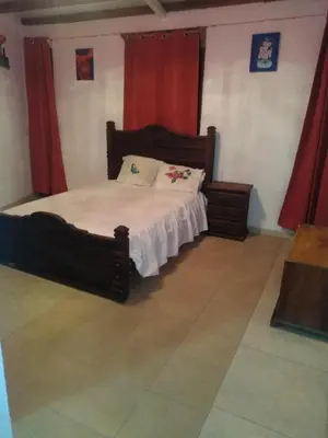 a bedroom with a wooden bed with red curtains at Hostel Paco House in Monteverde Costa Rica