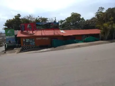 a building with a red roof next to a street at Hostel Paco House in Monteverde Costa Rica