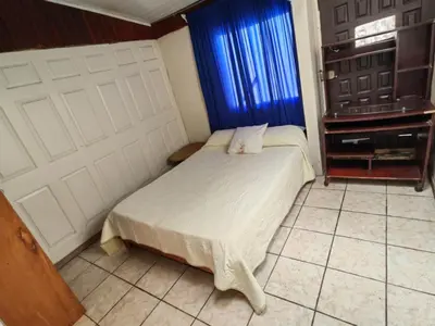 a bedroom with a bed and two white garage doors at Hostel Paco House in Monteverde Costa Rica