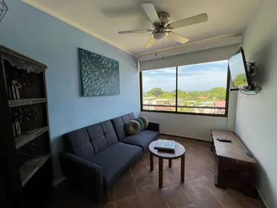 a living room with a couch and a large window at Tropical Gardens Suites and Apartments in Coco