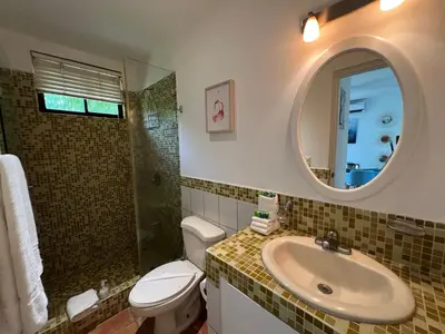a bathroom with a sink and a toilet and a mirror at Tropical Gardens Suites and Apartments in Coco