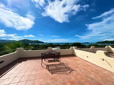 a bench on a balcony with a blue sky at Tropical Gardens Suites and Apartments in Coco