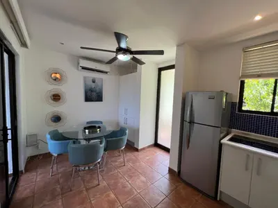 a kitchen with a table and chairs and a refrigerator at Tropical Gardens Suites and Apartments in Coco