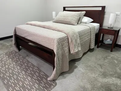 a bedroom with a bed with a blanket and two tables at Casa del Cafe-Familiar in Heredia