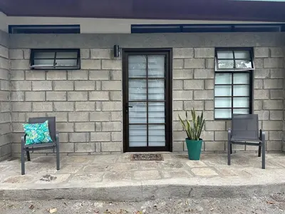 a house with two chairs and a door at Casa del Cafe-Familiar in Heredia