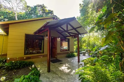 a yellow building with an umbrella on a patio at Cabañas Valle Campanas - Monteverde, Costa Rica in Monteverde Costa Rica