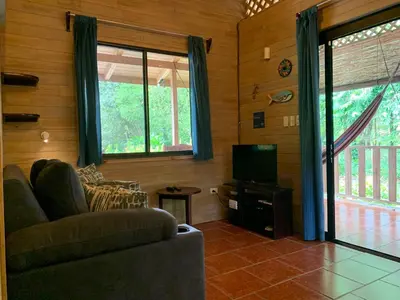 a living room with a couch and a television at Ocean Melody 2 in Uvita