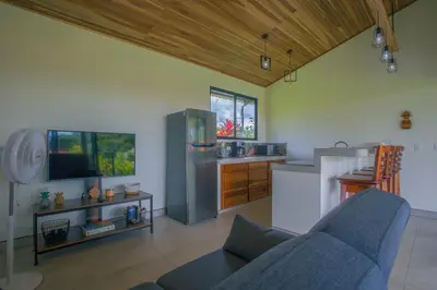 a living room with a blue couch and a kitchen at La Finca Lodge in Fortuna