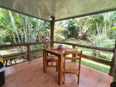 a table and chairs on a porch with a view of trees at Arenal Homes La Fortuna in Fortuna