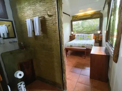 a bathroom with a shower and a bed in a room at Arenal Homes La Fortuna in Fortuna