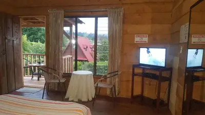 a bedroom with a bed and a television and a balcony at Hotel Chalets Los Volcanes in Alajuela City