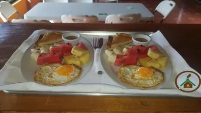 two breakfast plates with eggs and fruit on a tray at Hotel Chalets Los Volcanes in Alajuela City