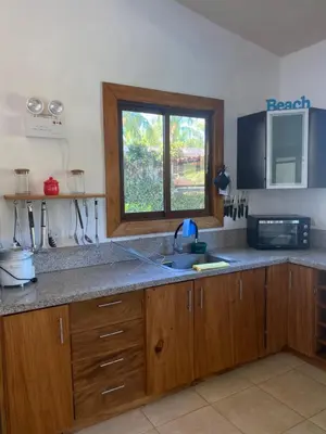 a kitchen with wooden cabinets and a sink and a window at Casa Piscina in Santa Teresa Beach