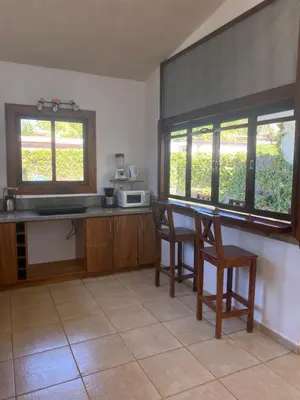 a kitchen with a table and chairs and windows at Casa Piscina in Santa Teresa Beach