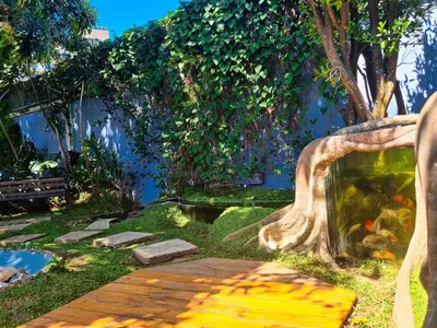 a garden with a fish pond and a wooden bridge at Casa Jardin del Mango in San José