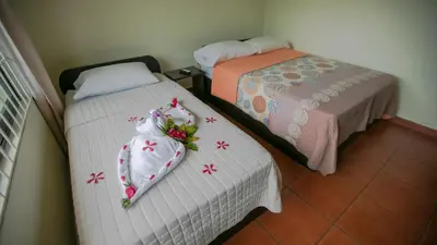 two beds in a room with white sheets and flowers at Condo's Vista Al Volcan in Fortuna
