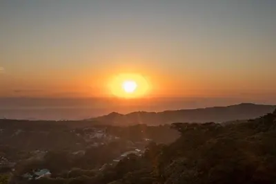 a sunset in the mountains with the sun setting at Hotel Flor de Bromelia in Monteverde Costa Rica