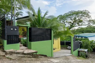 a green and black gate in front of a house at Yellow House in Quepos