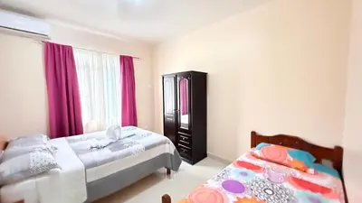 a bedroom with two beds and purple curtains at Yellow House in Quepos