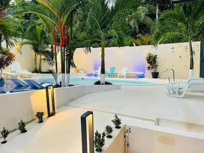 a swimming pool with palm trees and chairs in a resort at Millenium Manuel Antonio Park and beach in Manuel Antonio