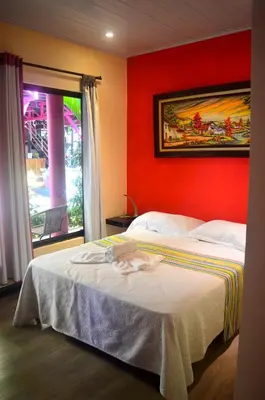 a bedroom with a bed with a red wall at Millenium Manuel Antonio Park and beach in Manuel Antonio