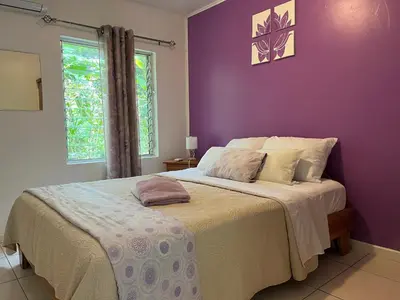 a bedroom with a large bed with a purple wall at Villas Majolana in Herradura