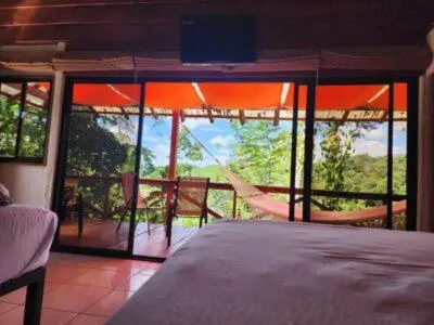 a bedroom with a view of a balcony with a hammock at Boca Tapada Lodge in Boca Tapada