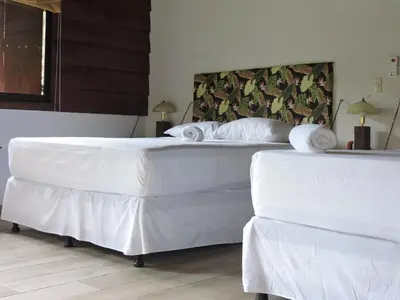 two beds in a room with white sheets and pillows at Boca Tapada Lodge in Boca Tapada