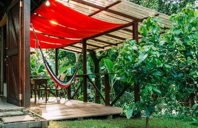 a red hammock hanging from a wooden deck at Boca Tapada Lodge in Boca Tapada