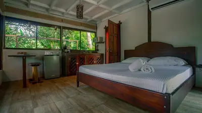 a bedroom with a bed and a table and windows at Boca Tapada Lodge in Boca Tapada