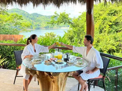 a man and woman sitting at a table with drinks at Isla Chiquita Glamping Hotel in Puntarenas