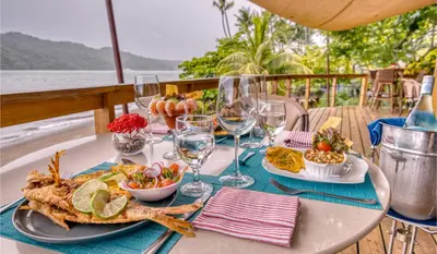 a table with a plate of food and wine glasses at Isla Chiquita Glamping Hotel in Puntarenas